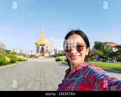 A young Asian tourist woman taking a selfie at the Statue of King Father Norodom Sihanouk Memorial in Phnom Penh city, Cambodia. Stock Photo