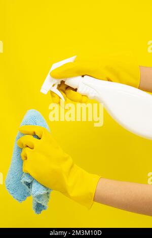 Cleaner concept, Hand in rubber gloves and holding spray bottle to spray cleaner on hand towel. Stock Photo