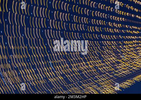 Abstraction blurred movement lights garlands. Golden lights of a blurred garland on the background of a purple blue sky. The concept of a night Stock Photo