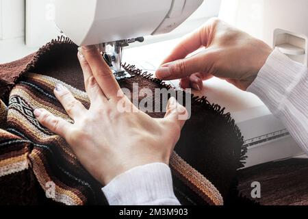 Woman's hands in the process of sewing a dress on the sewing machine. Tailoring environment. Sewing business concept Stock Photo