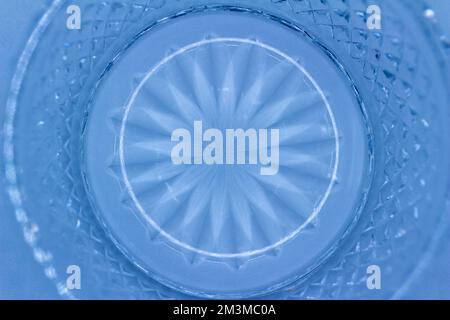 Macro abstract texture background of a round crystal glass surface with a sunburst design surrounded by diamond cuts, in the color of light blue Stock Photo