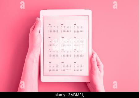 tablet computer with app calendar for unspecified unknown date year without date in womans hands. business or to do list goals. top view, flat lay. to Stock Photo