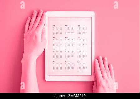 tablet computer with app calendar for unspecified unknown date year without date in womans hands. business or to do list goals. top view, flat lay. to Stock Photo