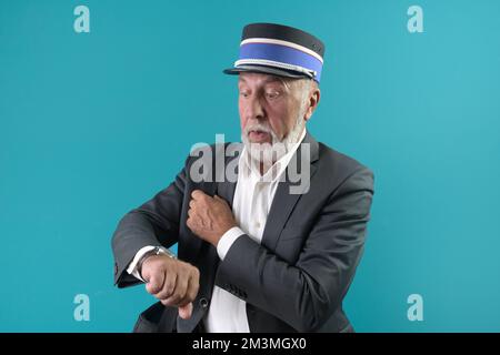 The train conductor warns the passenger about the time of departure of the train. On a blue background Stock Photo