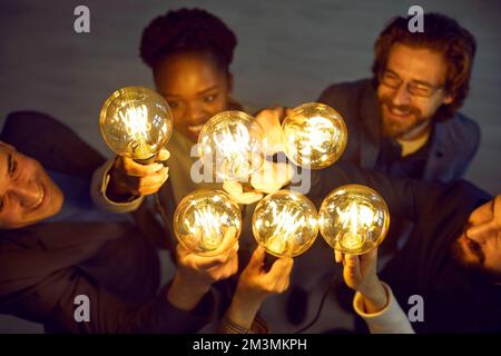 Bright glowing light bulbs in hands of various people as symbol of new creative ideas. Stock Photo