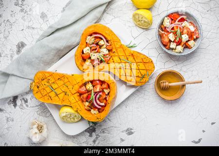 Halved roasted butternut squash with spicy vegetable filling and feta cheese Stock Photo