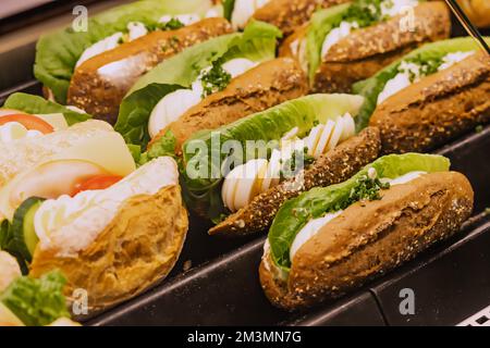 Variety of tasty sandwiches with salad and eggs in the window of a store or supermarket. Snacks and fastfood concept Stock Photo