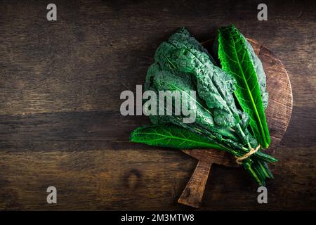 Palm kale, black cabbage - Cavolo nero black curly kale. Nero di Toscana (Brassica oleracea) on cutting board Stock Photo