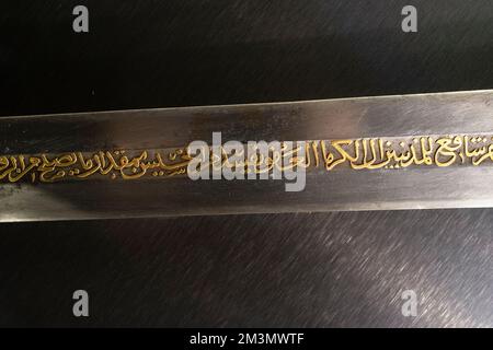 A closeup of a sword surface with Arabic calligraphy isolated on a black background. Stock Photo