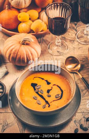 Pumpkin cream soup with pumpkin seeds on decorated kitchen table Stock Photo