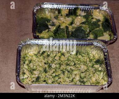 photo of sliced broccoli lying in a disposable baking dish on the kitchen table Stock Photo