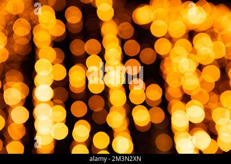 Festive bright blurred golden background. On Christmas black curtain, yellow bokeh lights are shining out of focus. Blank for postcards, place for tex Stock Photo