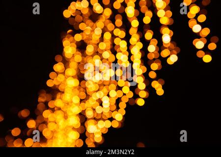 Festive bright blurred golden background. On Christmas black curtain, yellow bokeh lights are shining out of focus. Blank for postcards, place for tex Stock Photo