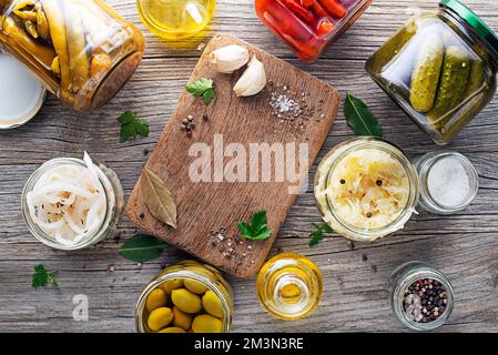 Canned and pickled vegetables in glass jars on wooden table. Preserved food Stock Photo