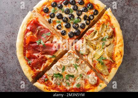 Pizza Four Seasons arranged into four sections, each representing a different season closeup on the board on the table. Horizontal top view from above Stock Photo