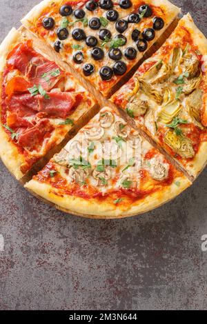 four seasons pizza quattro stagioni made with tomato sauce, mozzarella cheese, ham, artichokes, olives and mushrooms closeup on the board on the table Stock Photo