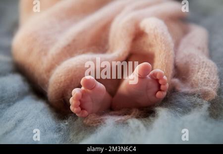 Close up crop legs of newborn baby wrapped in warm knitted blanket Stock Photo