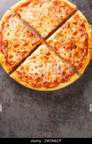 Authentic traditional New York City style pizza pie closeup on the board on the table. Vertical top view from above Stock Photo