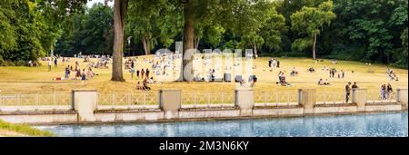 30 July 2022, Cologne, Germany: Many people and students relax in the city park by the pond on a summer day off Stock Photo