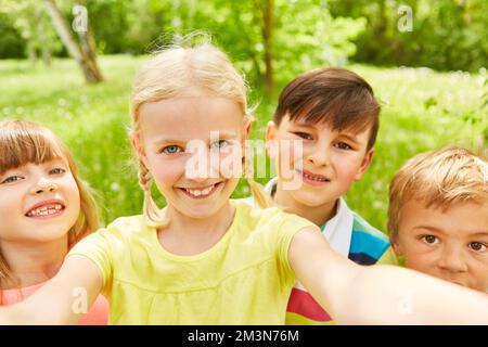 Portrait of smiling girl taking selfie with friends while spending leisure time in park Stock Photo
