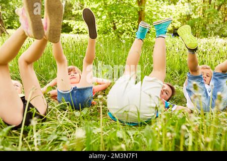 Multiracial boys and girls with legs up lying down in meadow during summer vacation Stock Photo