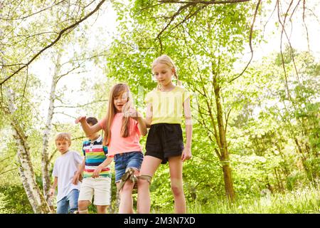 Multiracial male and female friends playing three legged race competition in garden during summer Stock Photo