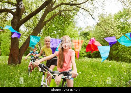 Happy group of children riding bikes in nature in summer Stock Photo