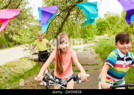 Multiracial female and male friends having fun while riding bicycles together in park Stock Photo