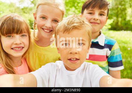 Portrait of boy taking selfie with male and female friends while spending leisure time in garden Stock Photo
