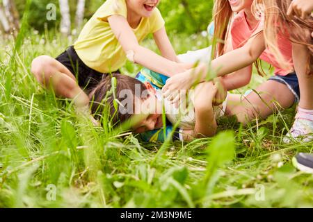 Girls scuffling over football in grass with competitive player at park during summer holiday Stock Photo