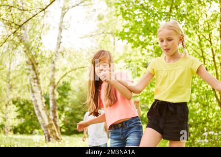 Female friends holding hands in three legged race competition at park during summer holiday Stock Photo