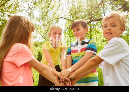 Multiracial male and female friends stacking hands together while playing in garden Stock Photo