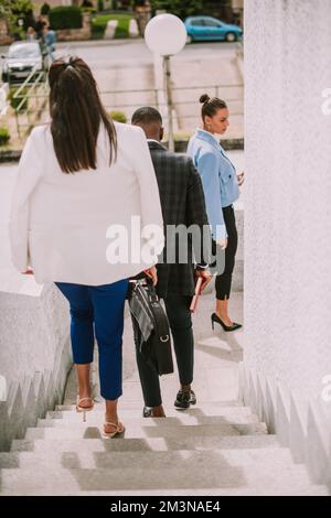 Three business people going down the stairs of the building Stock Photo