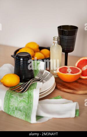 Fresh citrus fruits, black glass and bottle of lemonade on wooden board, space for text. Healthy summer drink, lemon and grapefruit Stock Photo