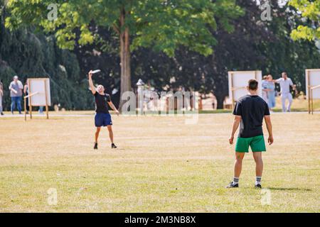 30 July 2022, Cologne, Germany: Athletic men play frisbee game in the park and throw a disc to each other Stock Photo