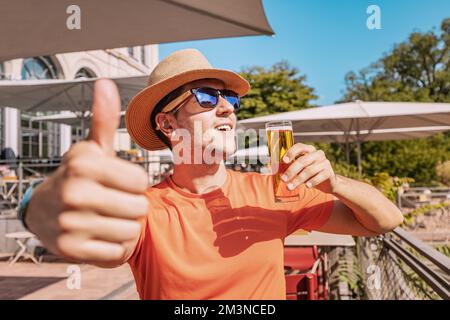 Man drinks and tasting a delicious craft traditional German and Cologne beer Kolsch in a pub or cafe overlooking the park or garden Stock Photo