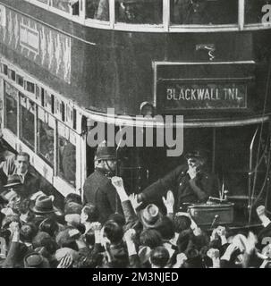 Anti-fascist crowds, some giving the Communist clenched fist salute, gather round a tram in the East End of London. A very large crowd gathered to protest against the proposed march by Sir Oswald Mosleys British Union of Fascists. The march was diverted by the police to avoid confrontation.     Date: 4 October 1936 Stock Photo
