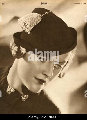 Mrs Bryan Guinness, formerly Diana Freeman-Mitford (1910 - 2003) and later Diana Mosley.  Pictured wearing a tasselled hat and clips at the neck which are 'contemporary fancies'.       Date: 1934 Stock Photo