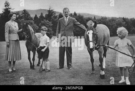 Prince Charles leading his pony William to his mother, Queen Elizabeth II. Princess Anne hold Greensleeves, patted by the Duke of Edinburgh, at Balmoral.     Date: 1955 Stock Photo