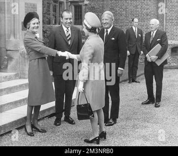 Queen Elizabeth II shakes hands with Mrs Pat Nixon, wife of the United States President, Richard Nixon who watches, along with British Prime Minister, Edward Heath, after the party had lunched at Chequers, the official British residence of the British premier.  Nixon was in England for a short visit as part of a European Tour in 1970.       Date: 1970 Stock Photo