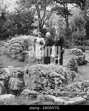 Queen Elizabeth II visiting the Chelsea Flower Show in 1955, inspecting a rock garden feature that has taken her attention.  She is conducted around the show by her maternal uncle, the Hon. David Bowes-Lyon.     Date: 1955 Stock Photo
