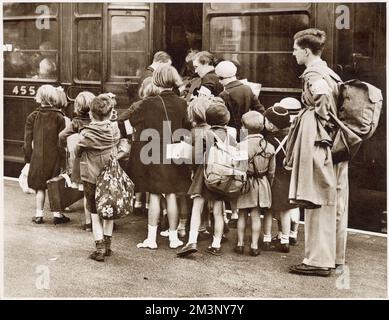 London's children evacuated at the beginning of World War Two: a first wave of 400000 children went on 1st September 1939, in the charge of 22000 teachers. Here a party is seen boarding a train at a main line station in the suburbs of London, equipped with gas masks and carrying their belongings in bags and haversacks. Stock Photo