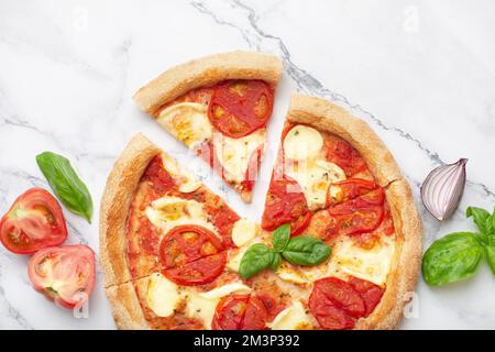 margherita pizza with tomatoes and basil on a white marble table Stock Photo