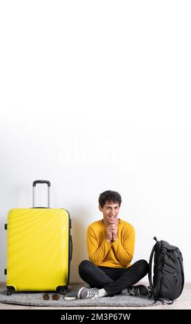 Funny happy traveler tourist arabic man in casual clothes with suitcase sit with hands on chest isolated on white background. Passenger travel abroad Stock Photo