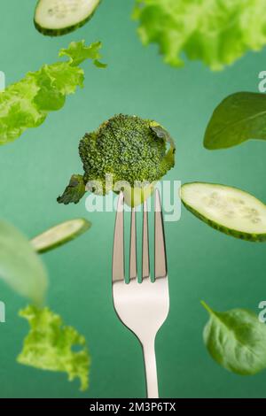 Broccoli on a fork and flying vegetables and greens. Green salad Stock Photo