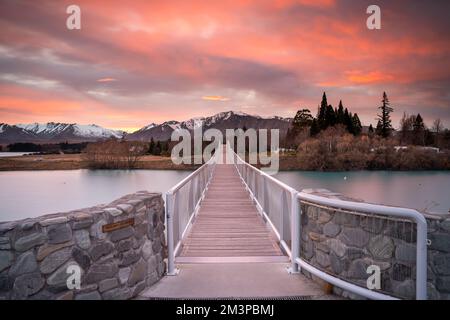 Sunrise view of the Maclaren Foot Bridge in late winter with beautiful snow capped Southern Alps mountain range in the background. New Zealand. Stock Photo