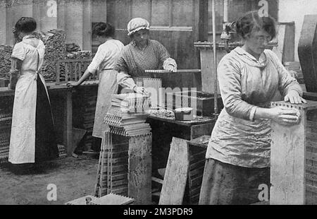 Young women manufacturing ammunition boxes, fixing together the dovetailed pieces at an unidentified British factory during the First World War.       Date: 1915 Stock Photo