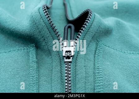 Close-up of the zipper on the green clothing. Zipper with lock. Fabric with zipper Stock Photo