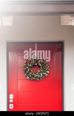 Christmas wreath hanging on a red wooden door Stock Photo