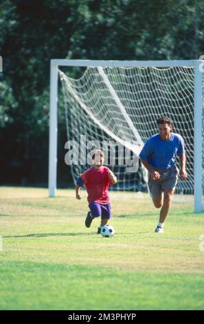 Father and son outside playing soccer Stock Photo